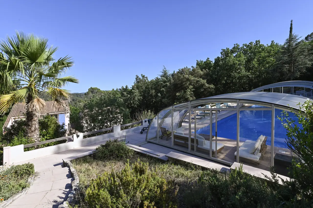 La piscine et son dôme amovible au milieu de la végétation